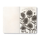 Open journal with lined pages beside a cream page of tall black sunflowers and bees, lettered: you never know how or when you'll have an impact