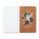 Open journal with lined pages beside a tan page of a pale hummingbird among green leaves and pink flowers