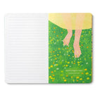 Open journal with lined pages and a breakout page of bare feet in a flowering meadow