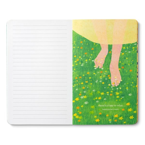 Open journal with lined pages and a breakout page of bare feet in a flowering meadow