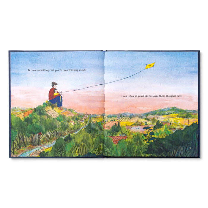 Open spread of a child on a hilltop flying a kite above a green valley