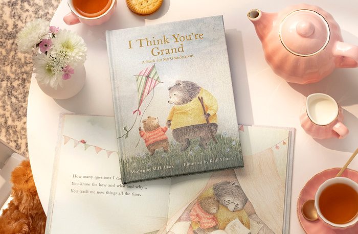 The book styled on a table with a pink teapot, cups and flowers