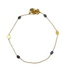 Fine gold chain necklace with dark blue-violet amethyst stones and brushed gold ovals, laid in a circle
