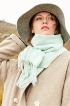 Model in a grey hat and beige coat with the Pistachio mint scarf outdoors