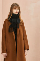 Ebony black merino scarf worn over a camel coat with fringe at the hem