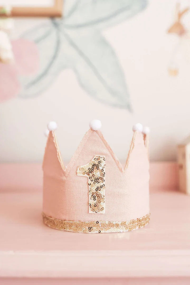 Pink first birthday crown with gold sequin one standing on a pink dresser