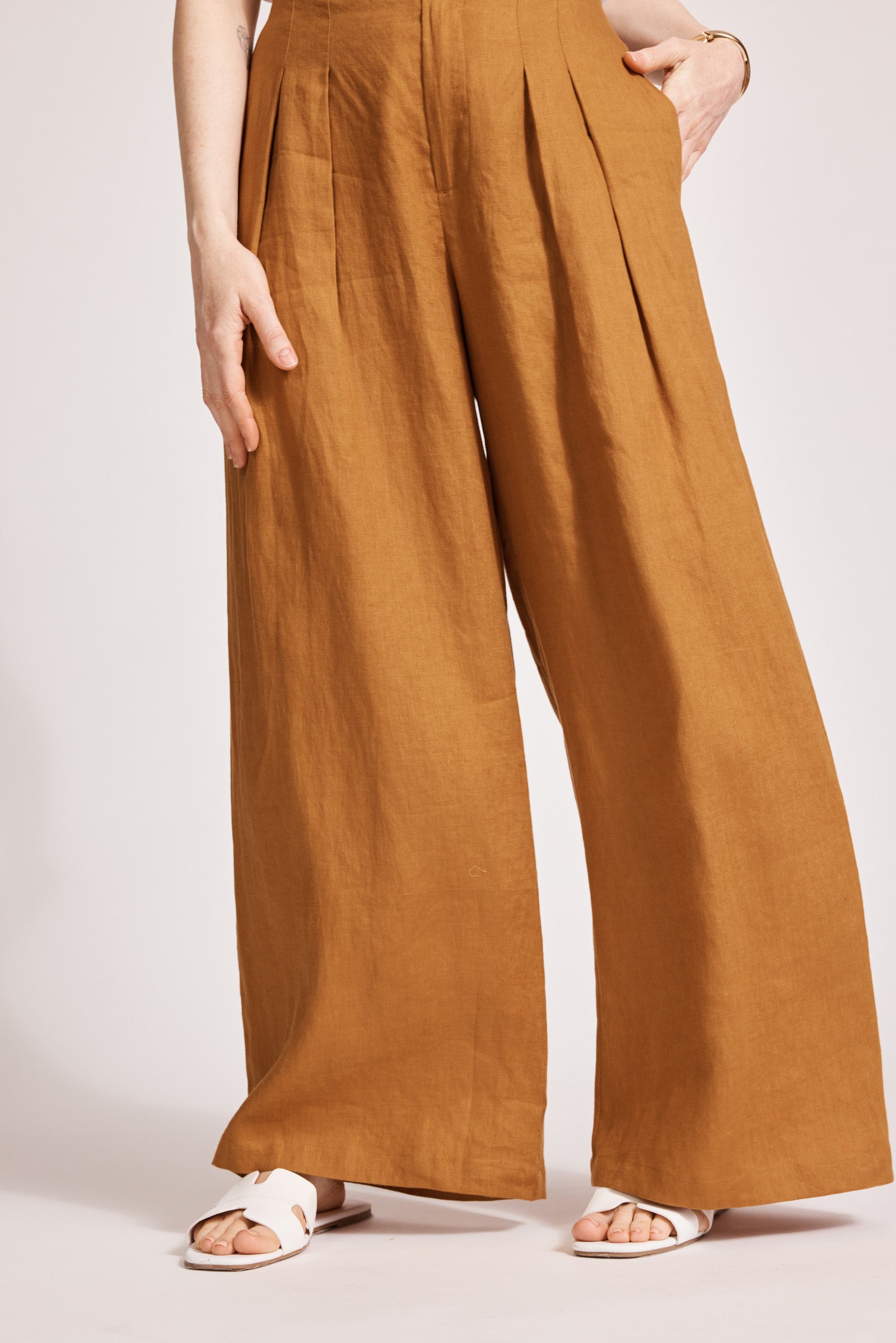 Close view of the wide caramel linen legs and white sandals