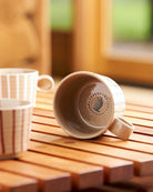 Archive mug tipped on its side showing the Robert Gordon base stamp, beside a chalk-striped mug