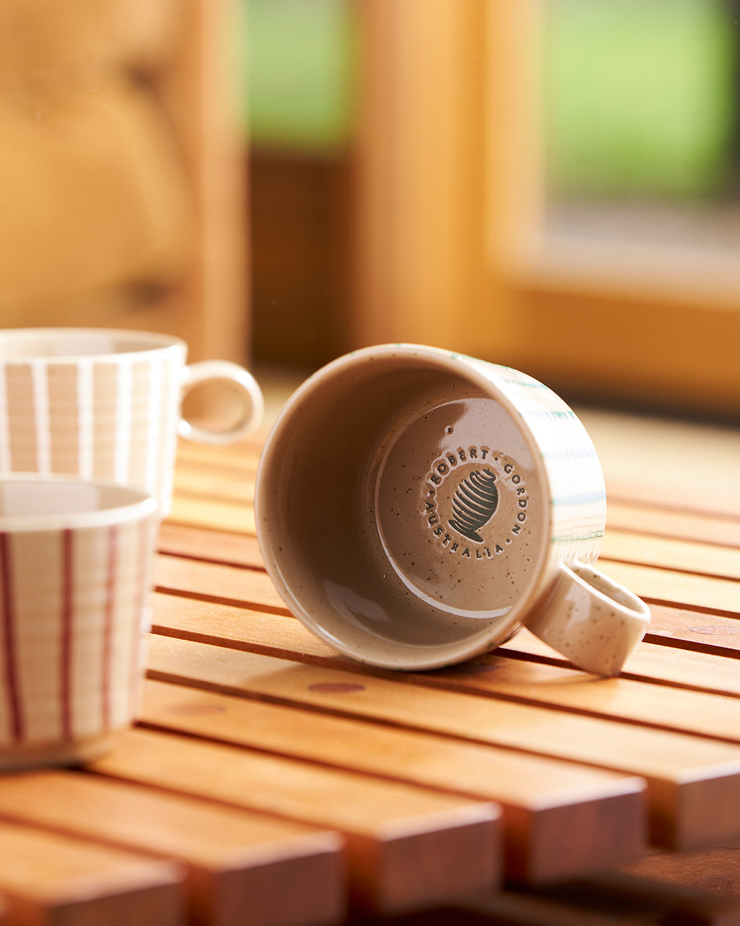 Archive mug tipped on its side showing the Robert Gordon base stamp, beside a chalk-striped mug