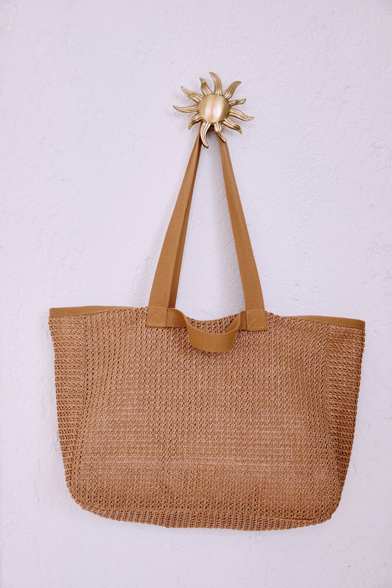 Artemis Beach Bag hanging from a gold sun-shaped hook