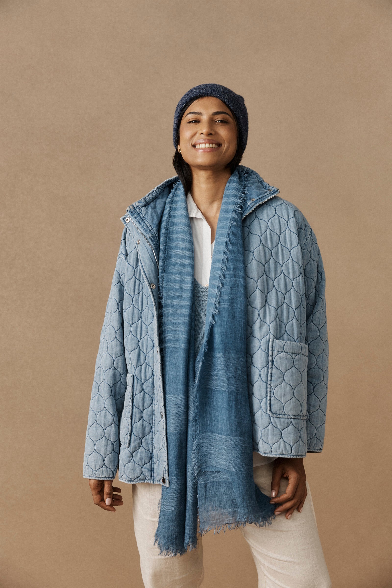 Smiling model in the blue Bodhi Scarf and quilted jacket