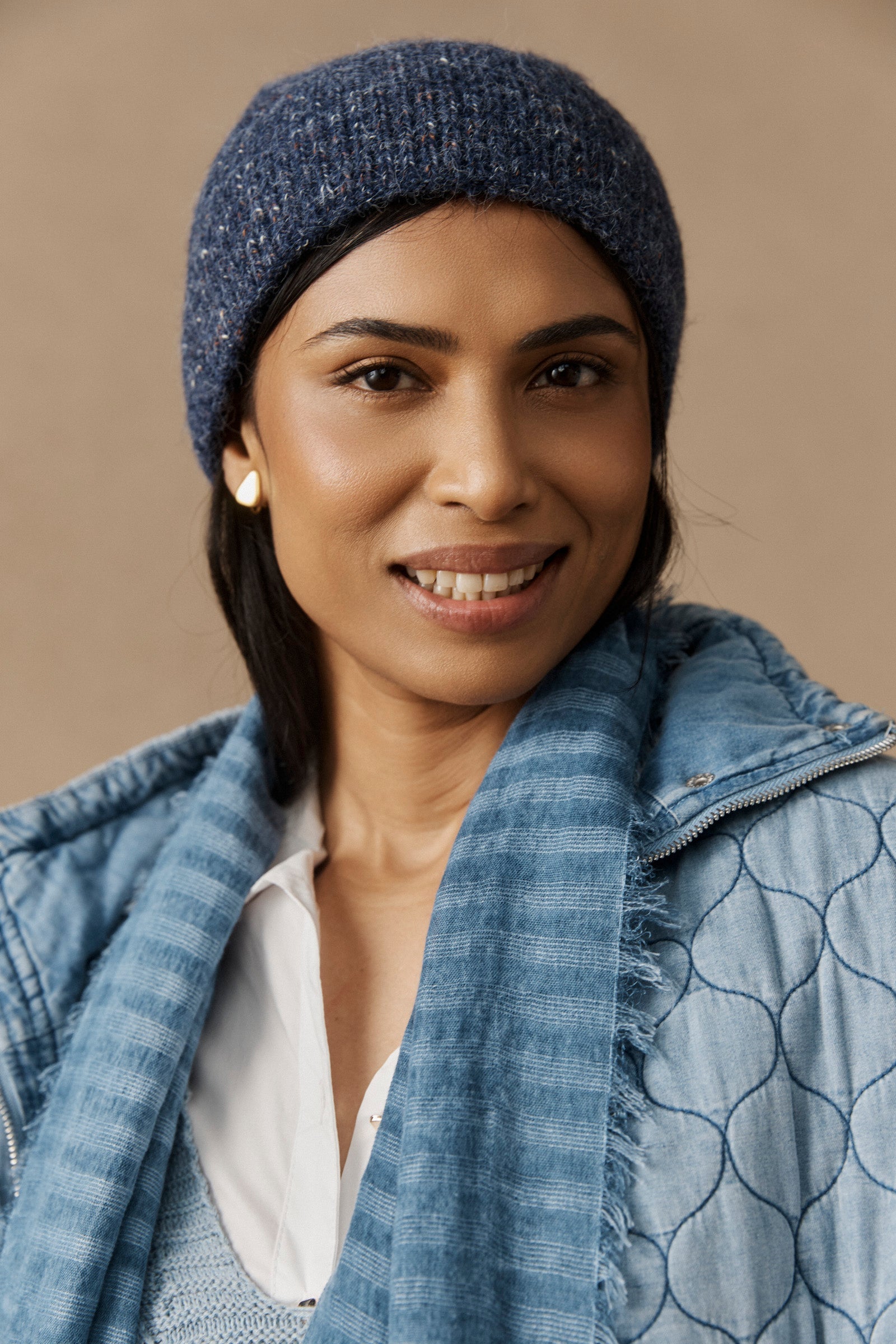 Smiling model in the denim marled beanie and blue jacket
