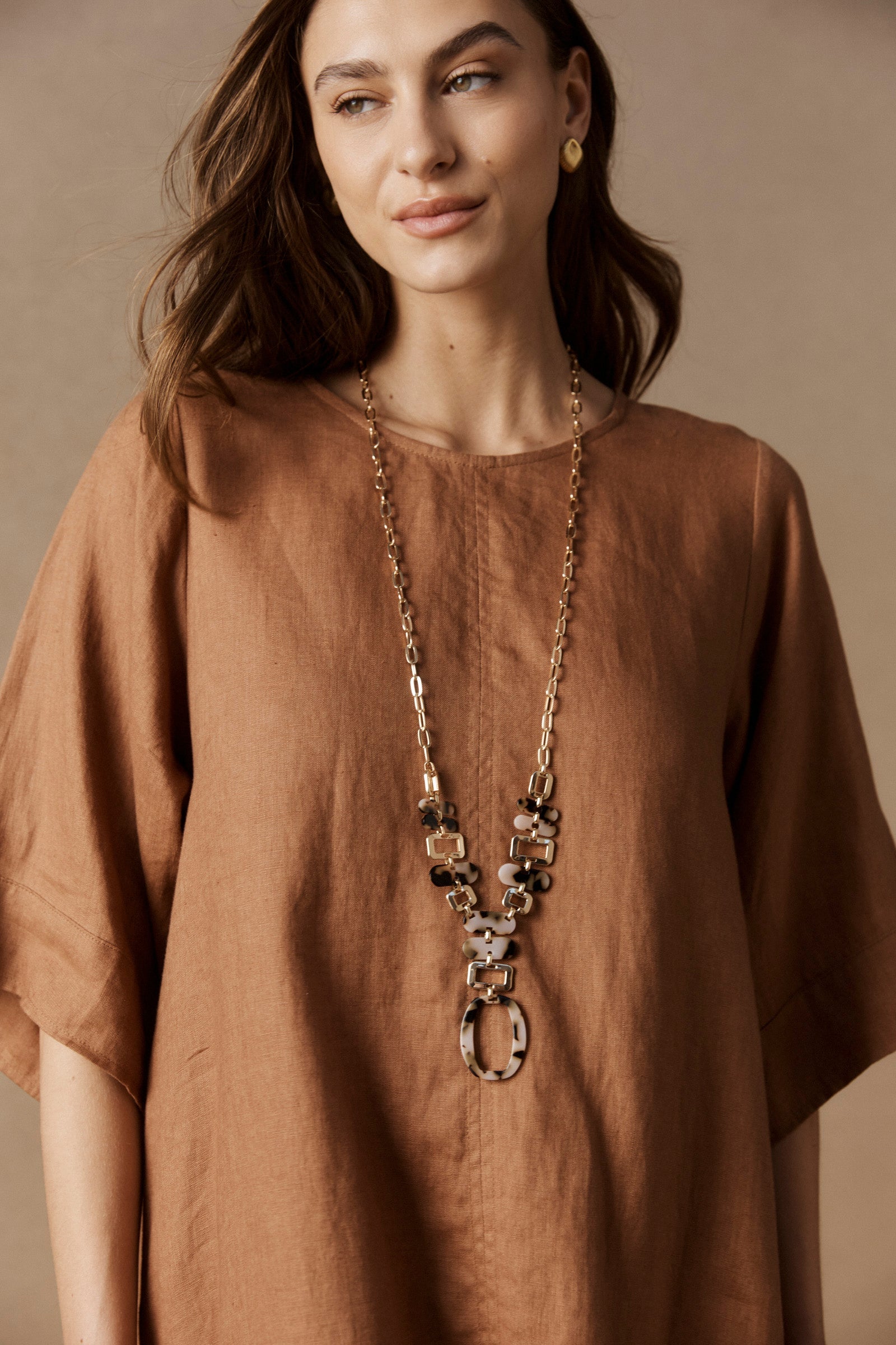Model wearing the Nomad Chain over a rust linen dress