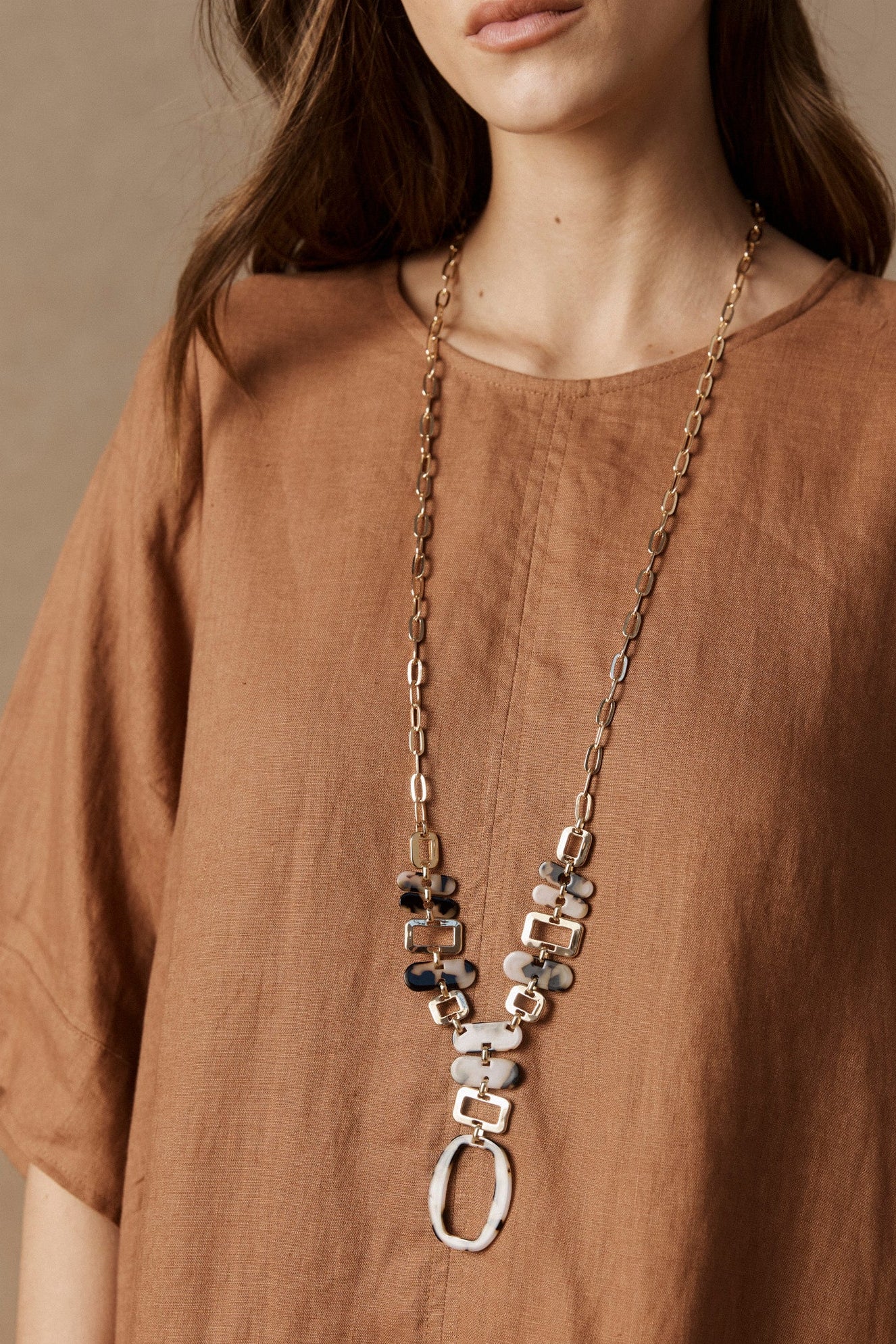 Model in a rust linen top wearing the long Nomad Chain