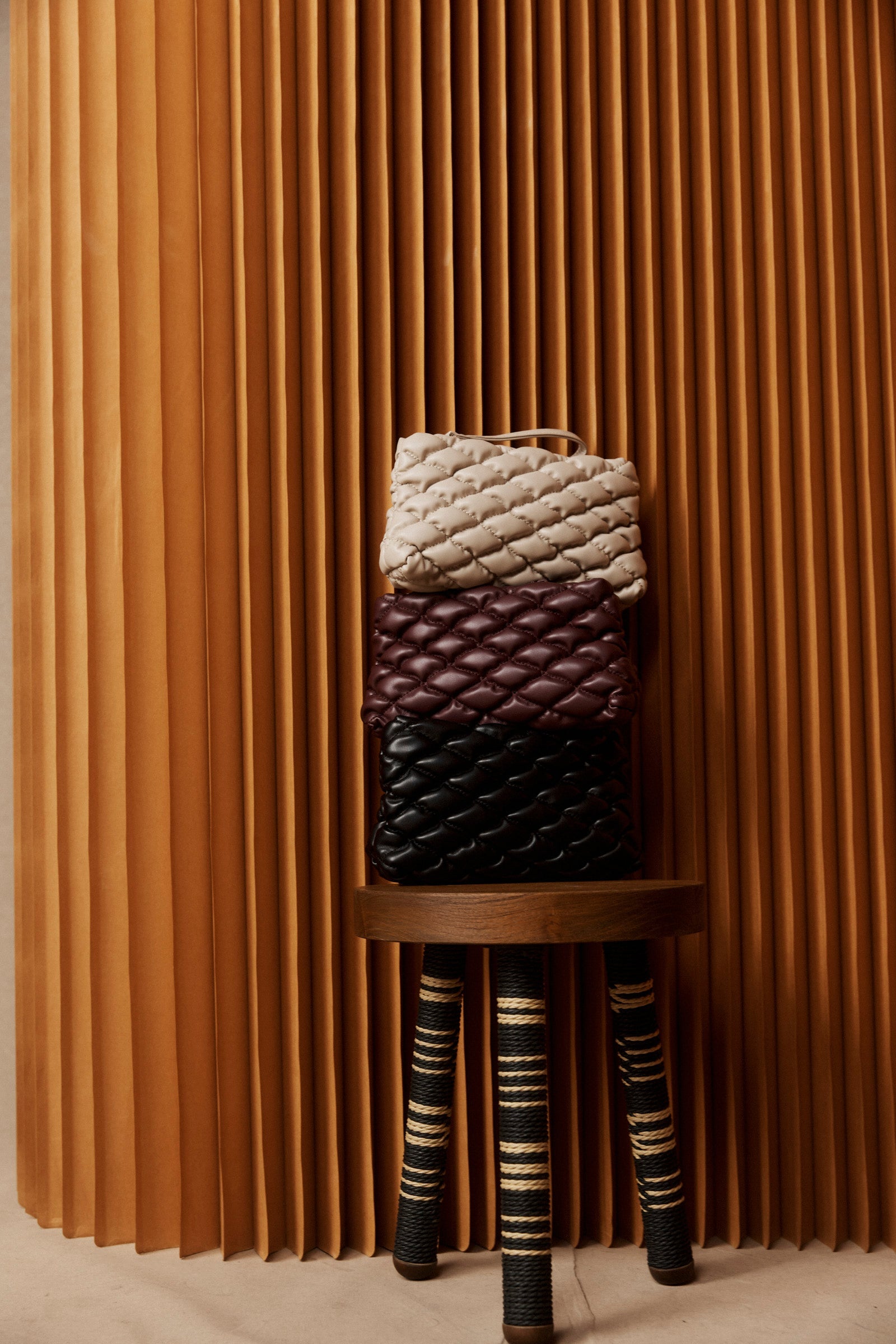 Quilted Zala Pouches on a stool in cream, mahogany and black