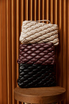 Cream, mahogany and black Zala Pouches stacked on a pedestal