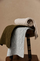 Rolled and draped scarves in cream, olive and grey on a chair