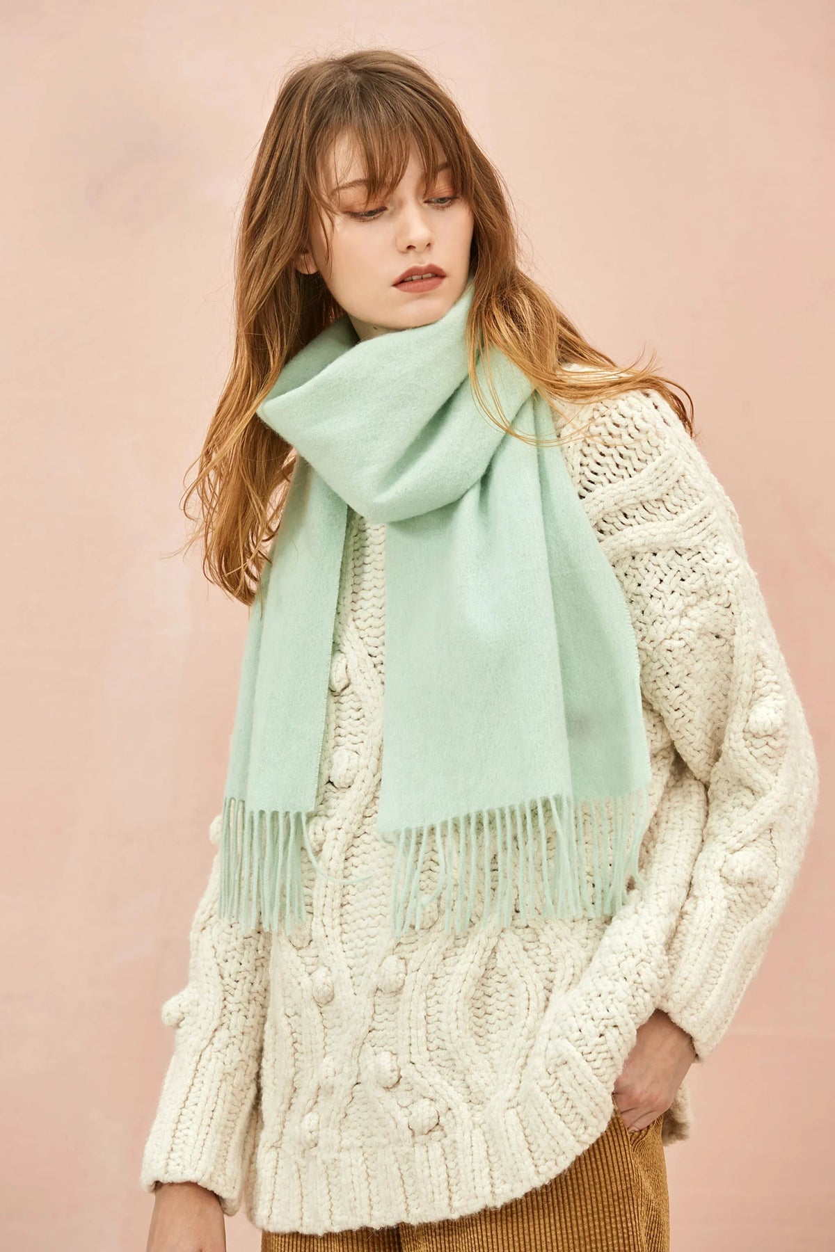 Pistachio mint scarf draped long over a cream jumper