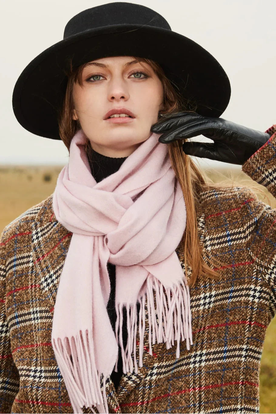 Close view of the Dahlia soft pink scarf with a black hat and checked coat