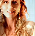 Smiling model with long strawberry-blonde hair wearing the gold linked-oval earring, in warm light