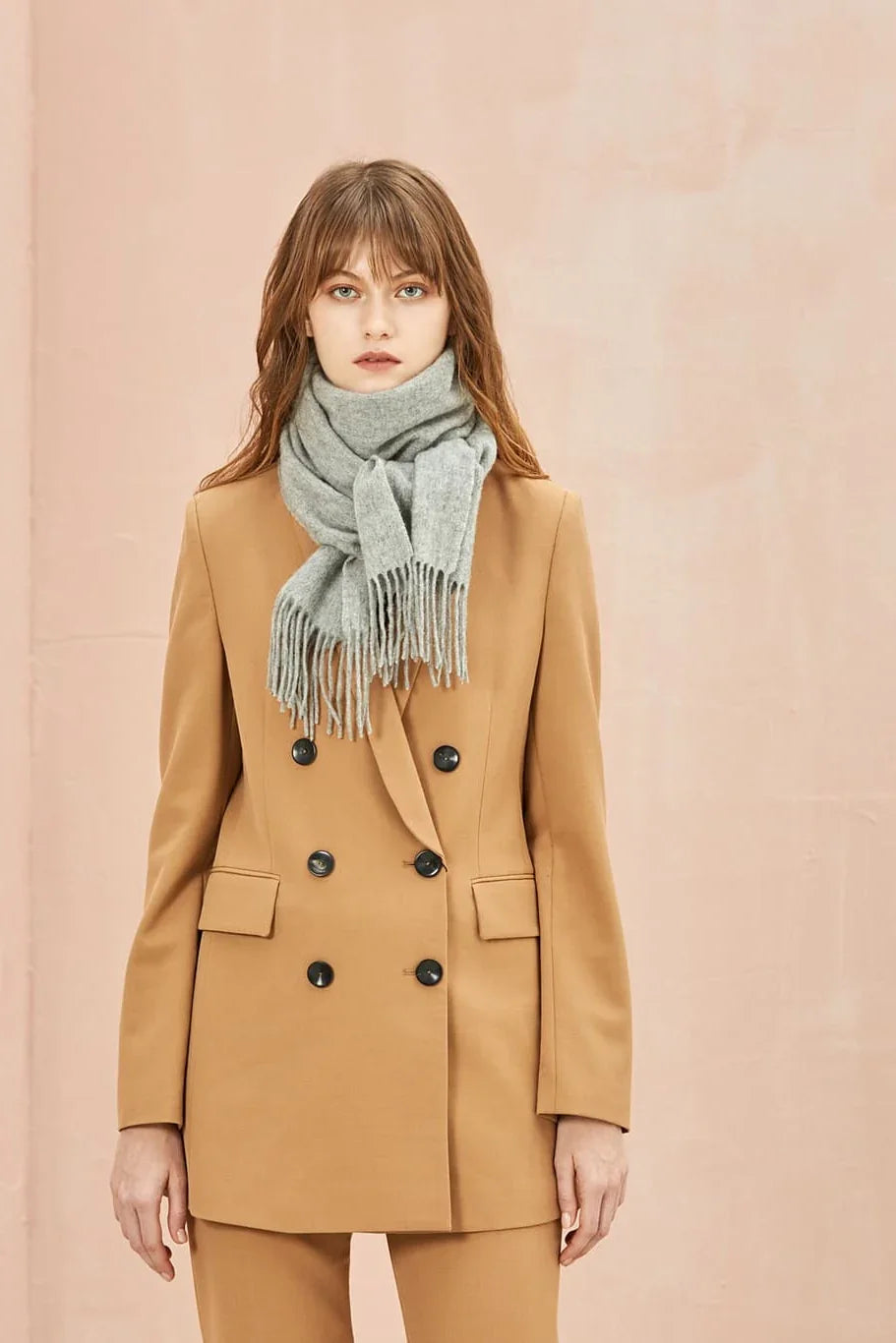 Model in a camel suit with the Quartz grey scarf knotted at the front