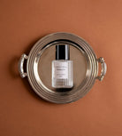 Sweet Pea perfume bottle seen from above on a silver tray against terracotta