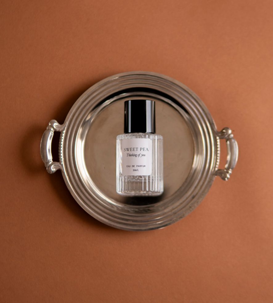 Sweet Pea perfume bottle seen from above on a silver tray against terracotta
