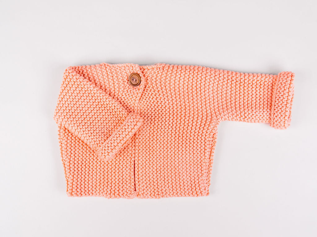Peach cardigan laid flat with one sleeve folded across.