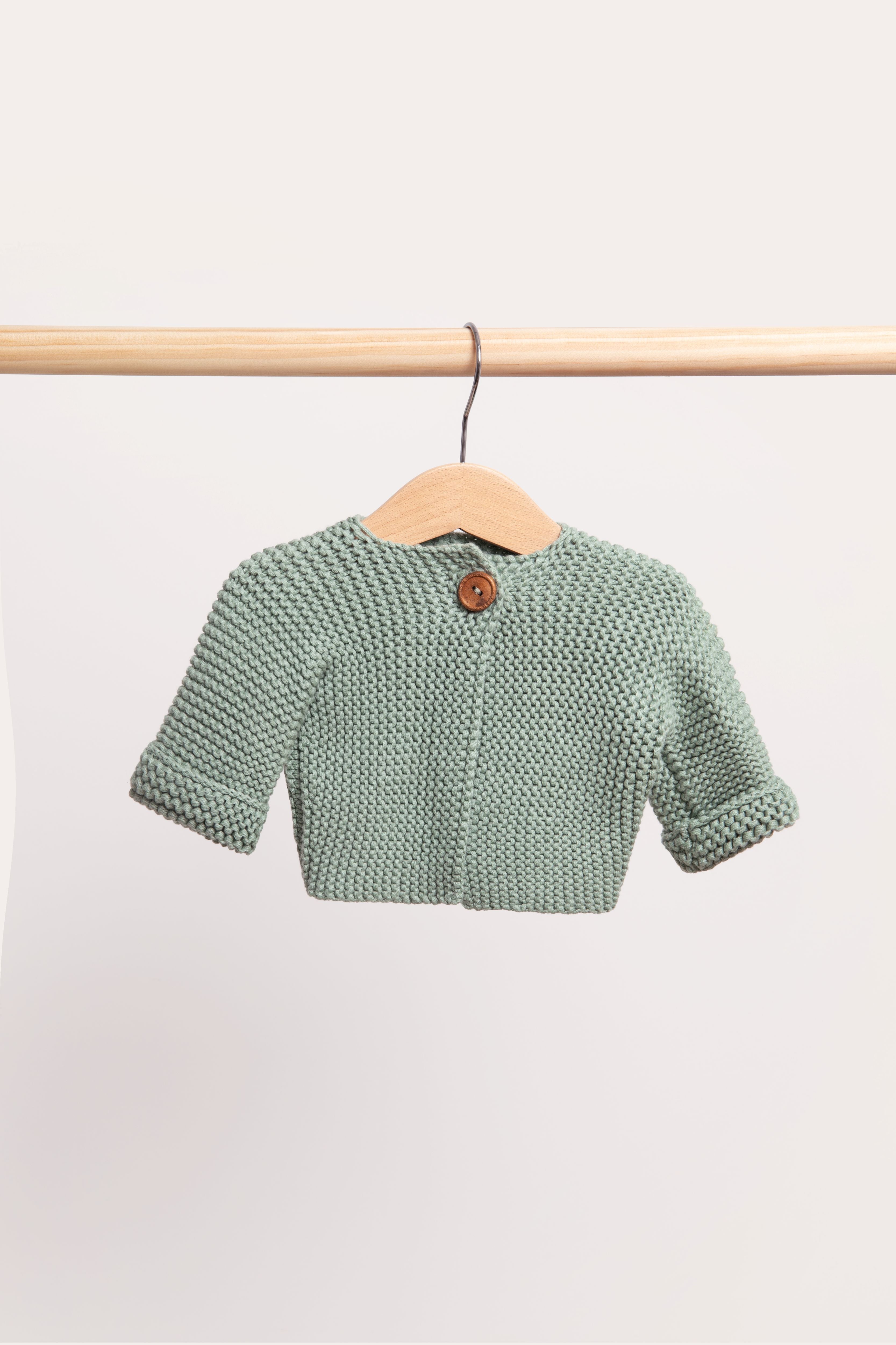 Duck Egg cardigan in a soft grey-green, on a wooden hanger from a timber rail.