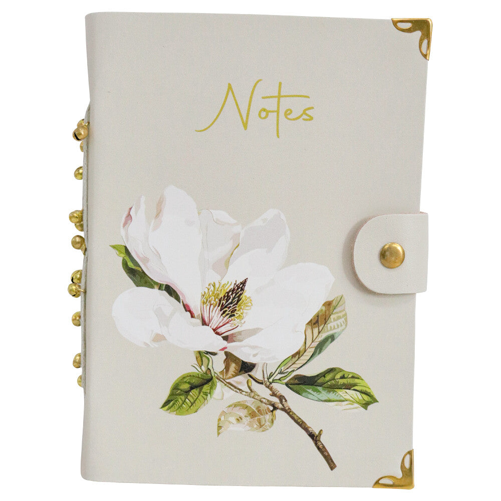Cream leather notebook with a white magnolia print, Notes in gold script, a press-stud tab, gold-tone corners and gold beads on the spine