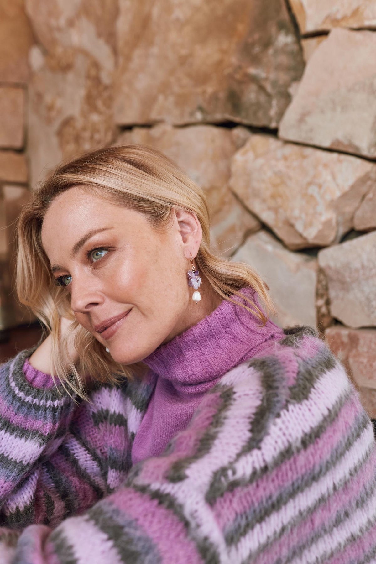 The Lilac earring worn with a purple and grey striped jumper