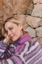 The Lilac earring worn with a purple and grey striped jumper
