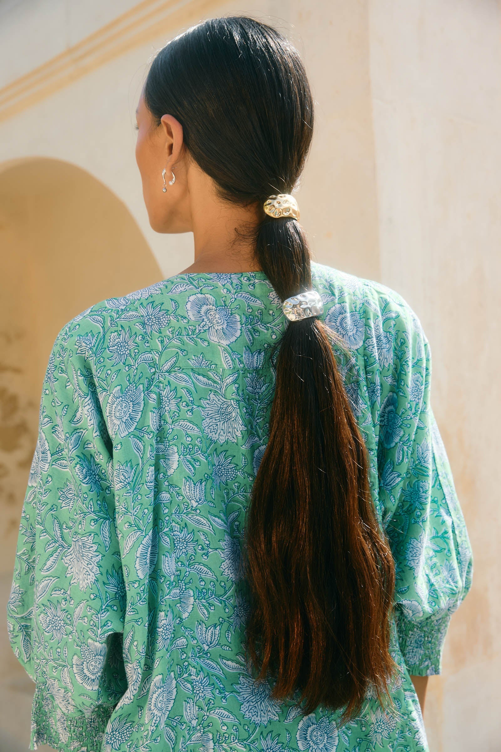 Back view of a woman with a long dark ponytail held by the silver cuff hair tie