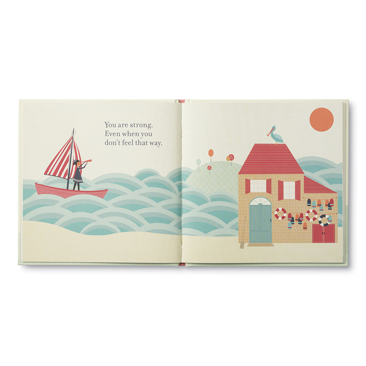 Open spread of a small sailing boat on blue waves beside a house with a red roof