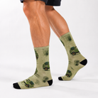Person's lower legs against a white background wearing the olive four-wheel drive socks, one foot flat and one lifted onto the toe.