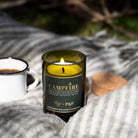 Lit Campfire candle on a striped grey throw with an enamel mug and its cork lid