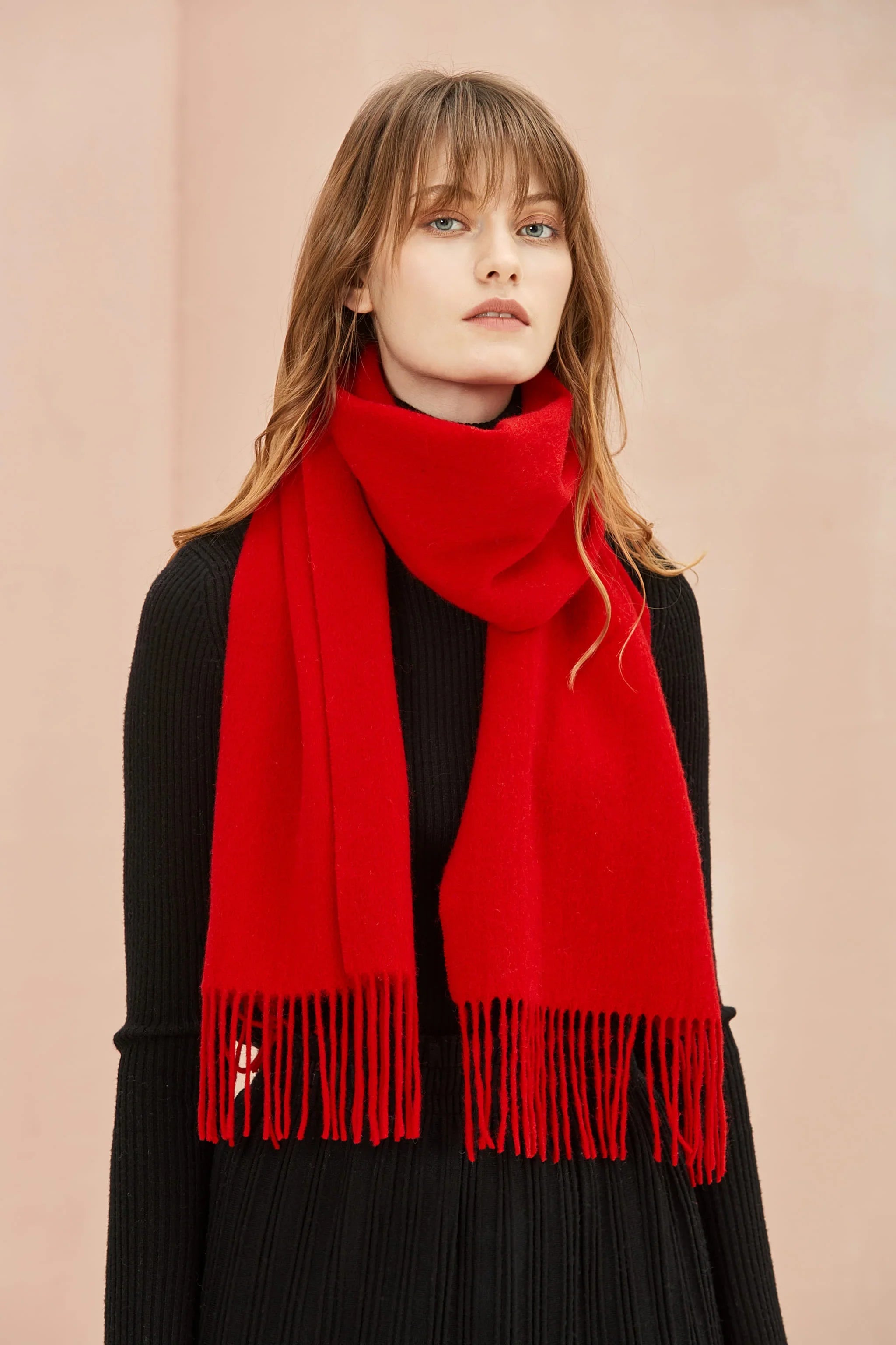 Raving Red solid merino scarf draped long over a black outfit, front view