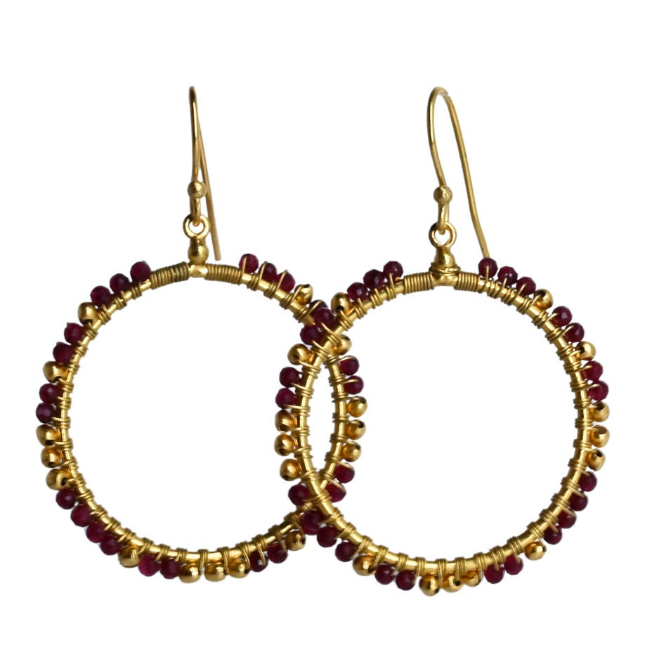 Overlapping gold hoop earrings wire-wrapped with wine-red ruby beads