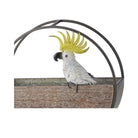 White sulphur-crested cockatoo with a bright yellow crest, perched on a curved dark metal arc that hooks over the edge of a pot.