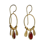 Fine gold hoop earrings with a faceted deep red carnelian teardrop between two gold petals