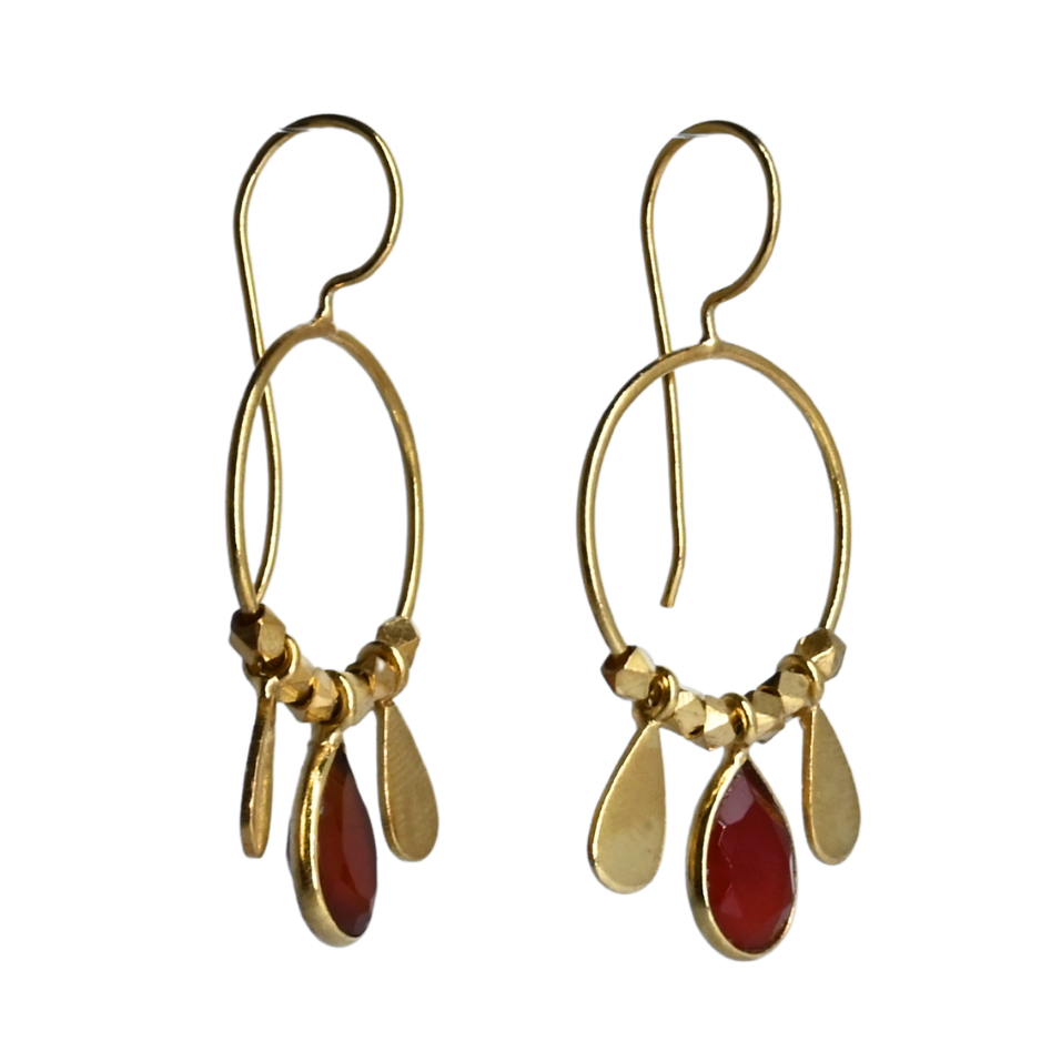 Fine gold hoop earrings with a faceted deep red carnelian teardrop between two gold petals