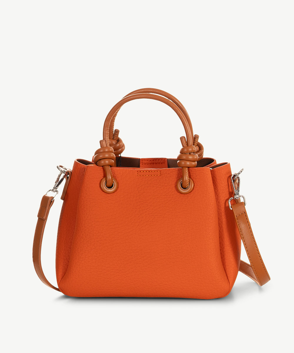 Burnt orange grained faux leather cross body bag with tan grab handles and a long tan strap.