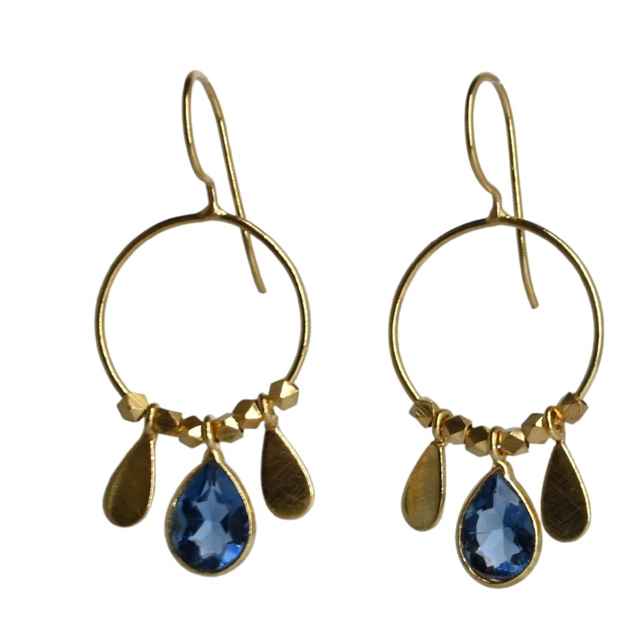 Fine gold hoop earrings with a faceted deep blue London blue topaz teardrop between two gold petals