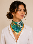 Model in a white shirt wearing a green and blue fern-print silk scarf with a golden satin border knotted at the neck