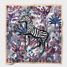 Zebra Purple silk scarf laid flat - a zebra among mauve, plum and indigo jungle foliage inside a soft peach border