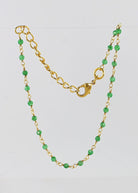 Fine gold chain bracelet with faceted green onyx beads draped on a stand