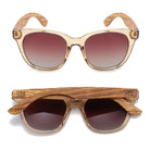 Two pairs of Lila Grace sunglasses in champagne, one front-on and one folded, showing the wood arms