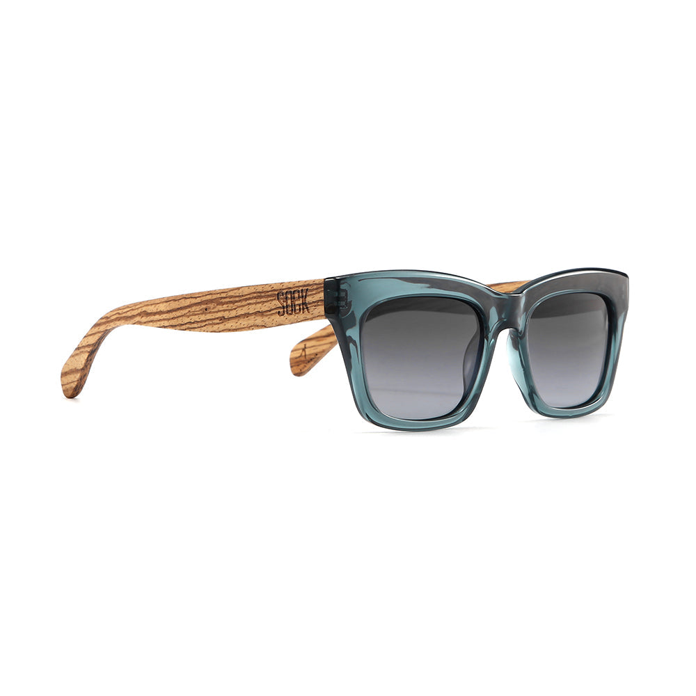 Morgan sunglasses at an angle: a squared indigo blue frame with pale grained wood arms and grey lenses