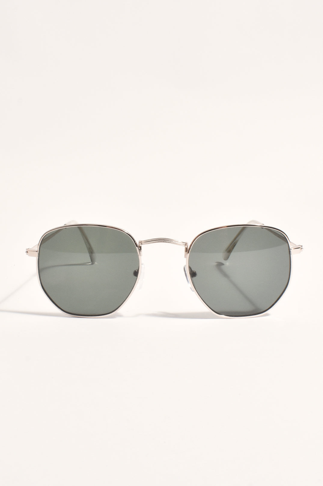 Metal frame hexagonal sunglasses with dark green-grey lenses, front view on a cream background