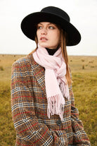 Model in a black hat and houndstooth coat wearing the Dahlia pink merino scarf outdoors